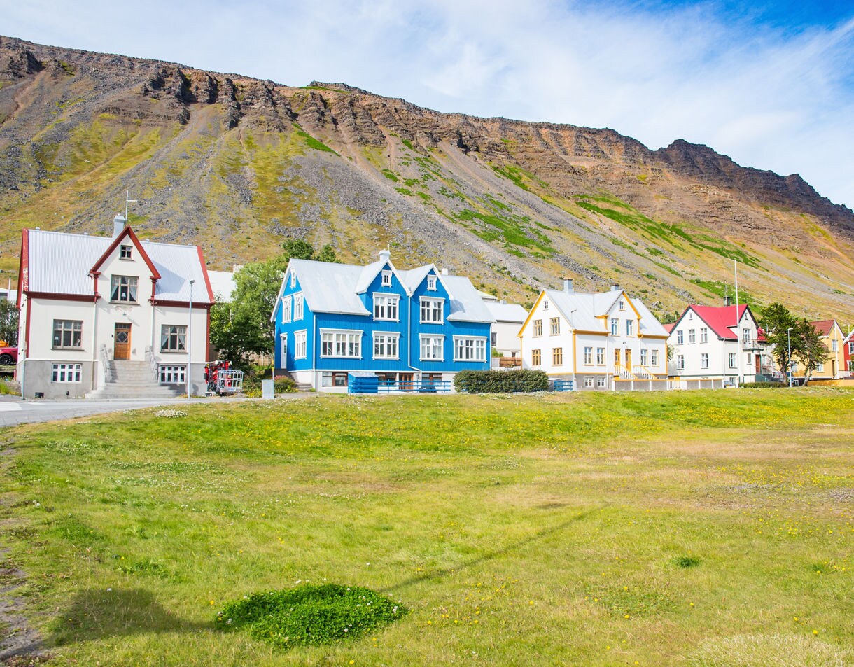 Colorful traditional houses in Ísafjörður with steep rocky mountains rising directly behind.