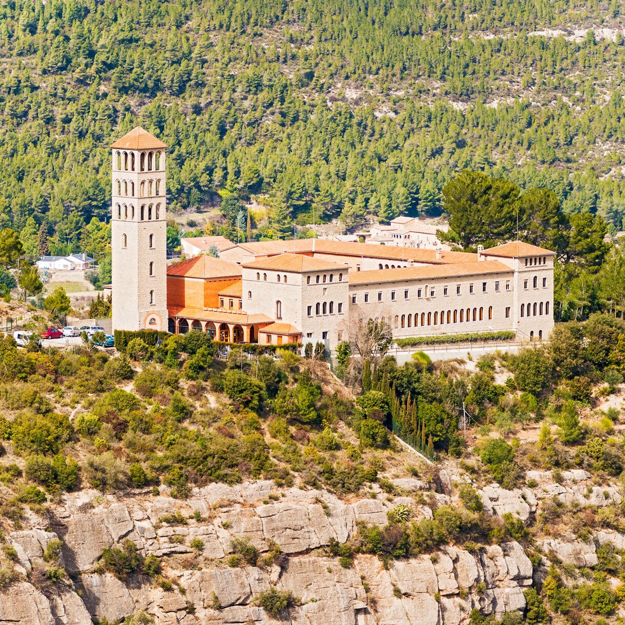 St. Benedict’s Monastery in Trinidad, a historic structure with a tall bell tower, terracotta roofs and stone walls, surrounded by green hills.