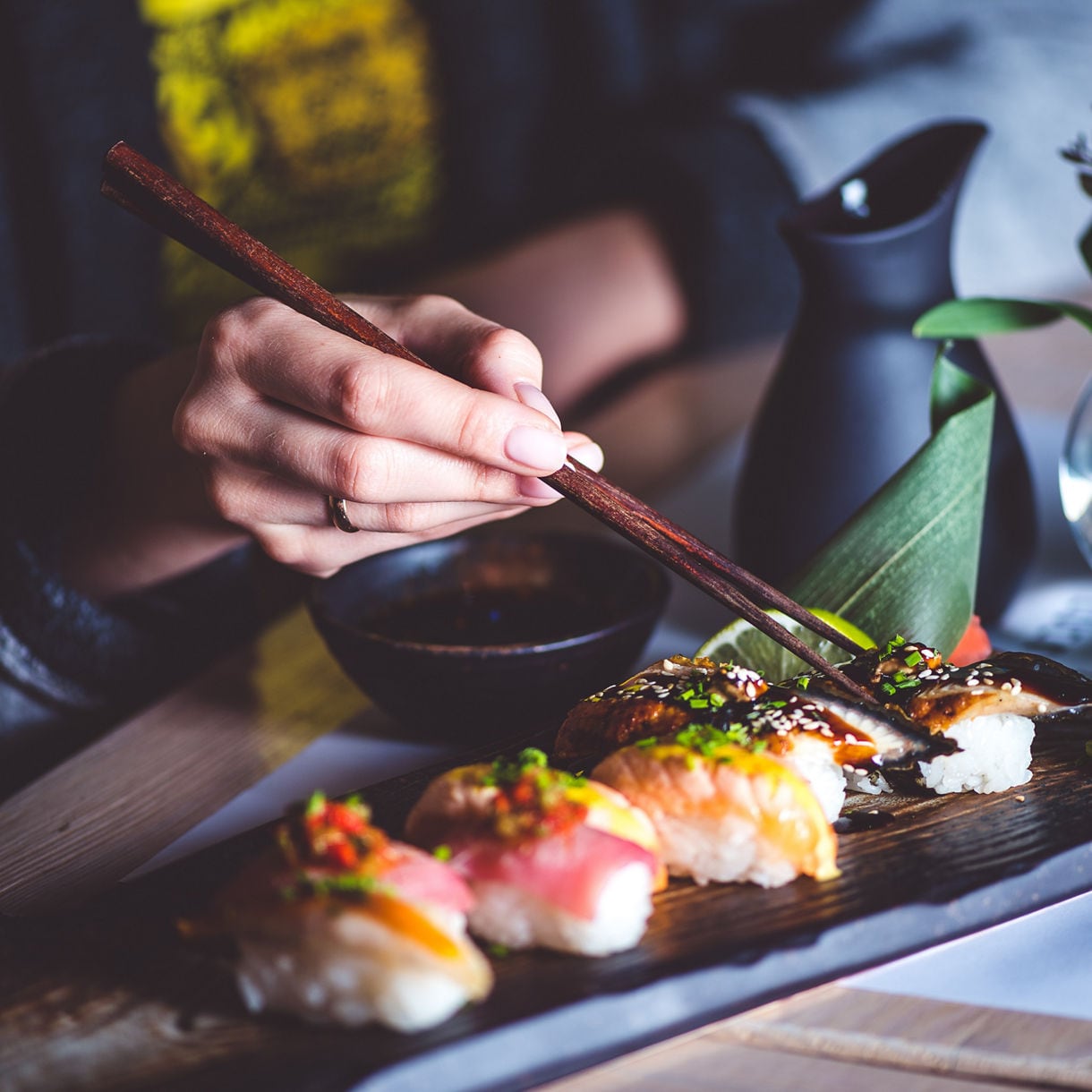 Man eating sushi set with chopsticks on restaurant