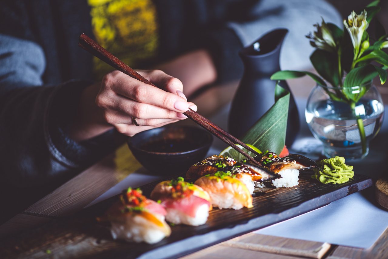 Man eating sushi set with chopsticks on restaurant