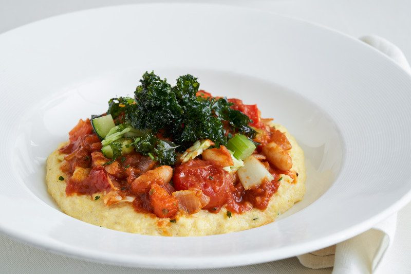 Polenta dish topped with seafood, tomato sauce and fresh kale.