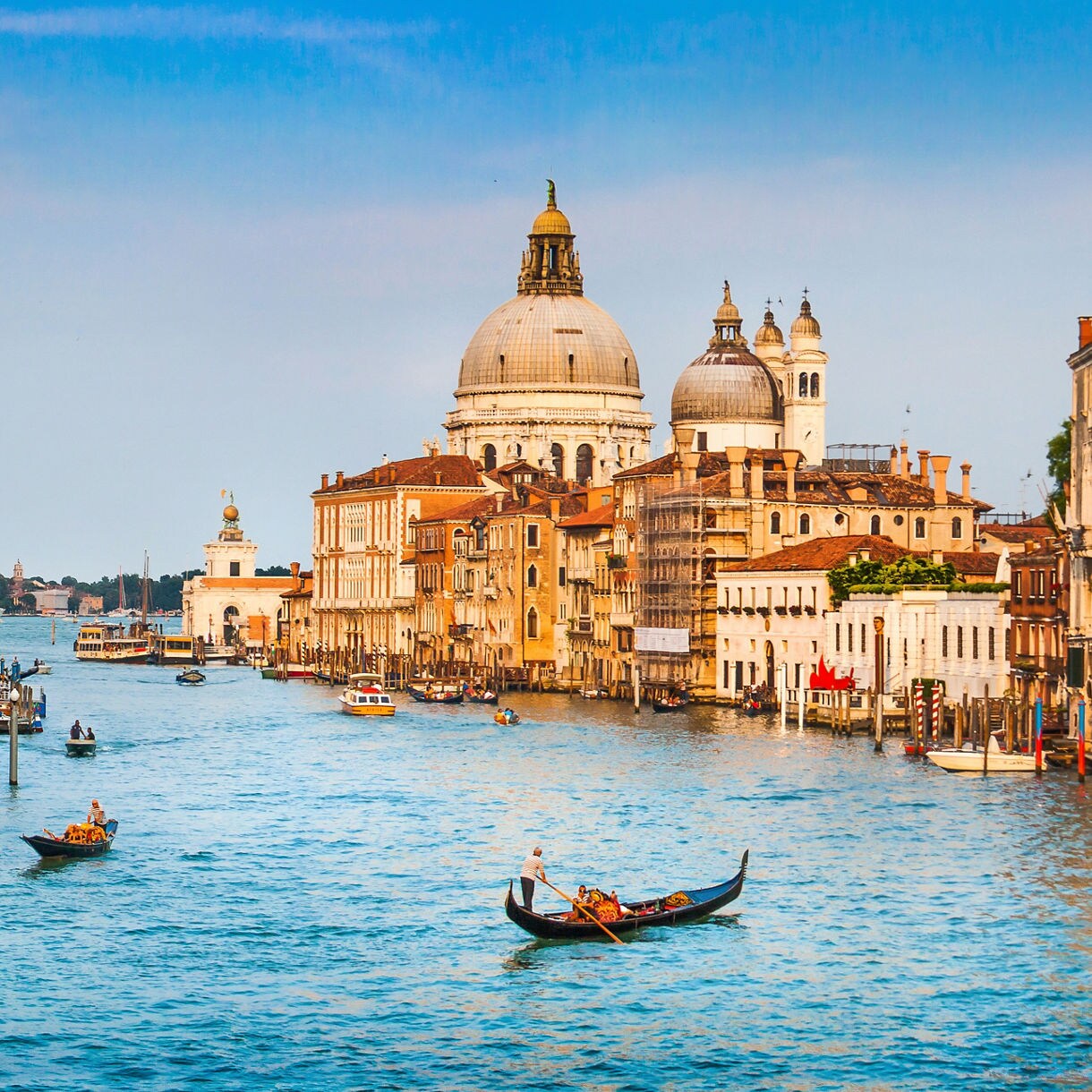 Gondolas on Venice’s Grand Canal with colorful historic buildings and Santa Maria della Salute in the background.