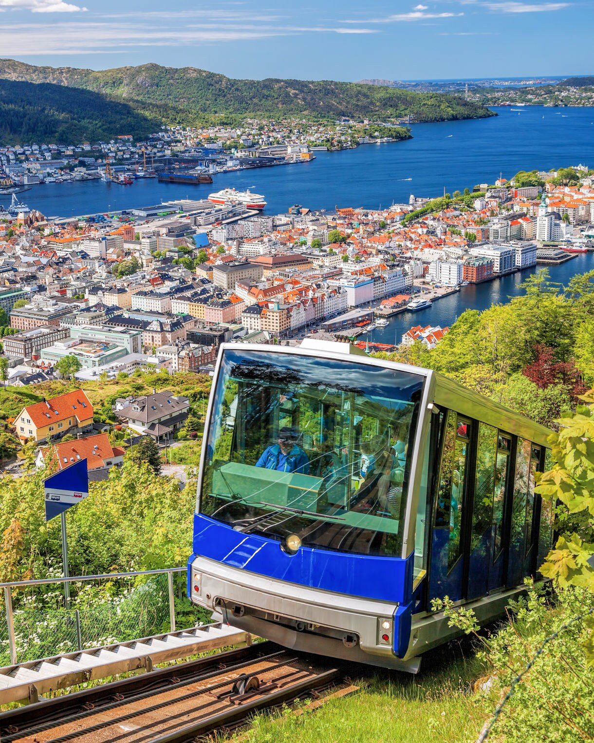 The Fløibanen funicular climbing Mount Fløyen with Bergen’s cityscape, harbor and surrounding mountains in the background.