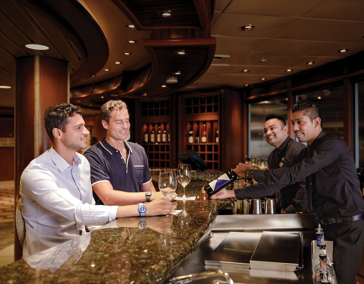 Elegant wine glasses being filled with red wine in an upscale bar setting with ambient lighting.