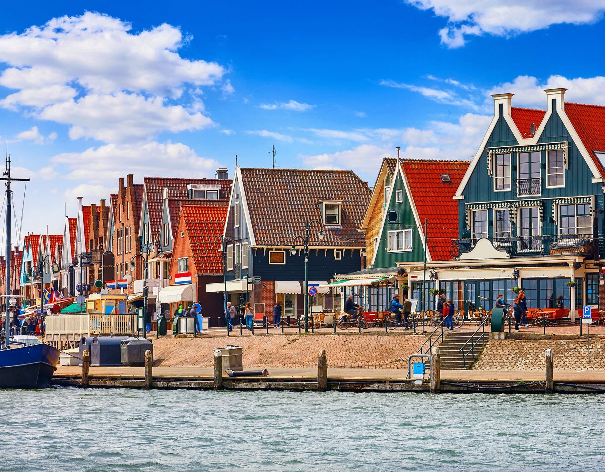 Colorful gabled houses with red roofs and shops along the harbor in Volendam, Netherlands.
