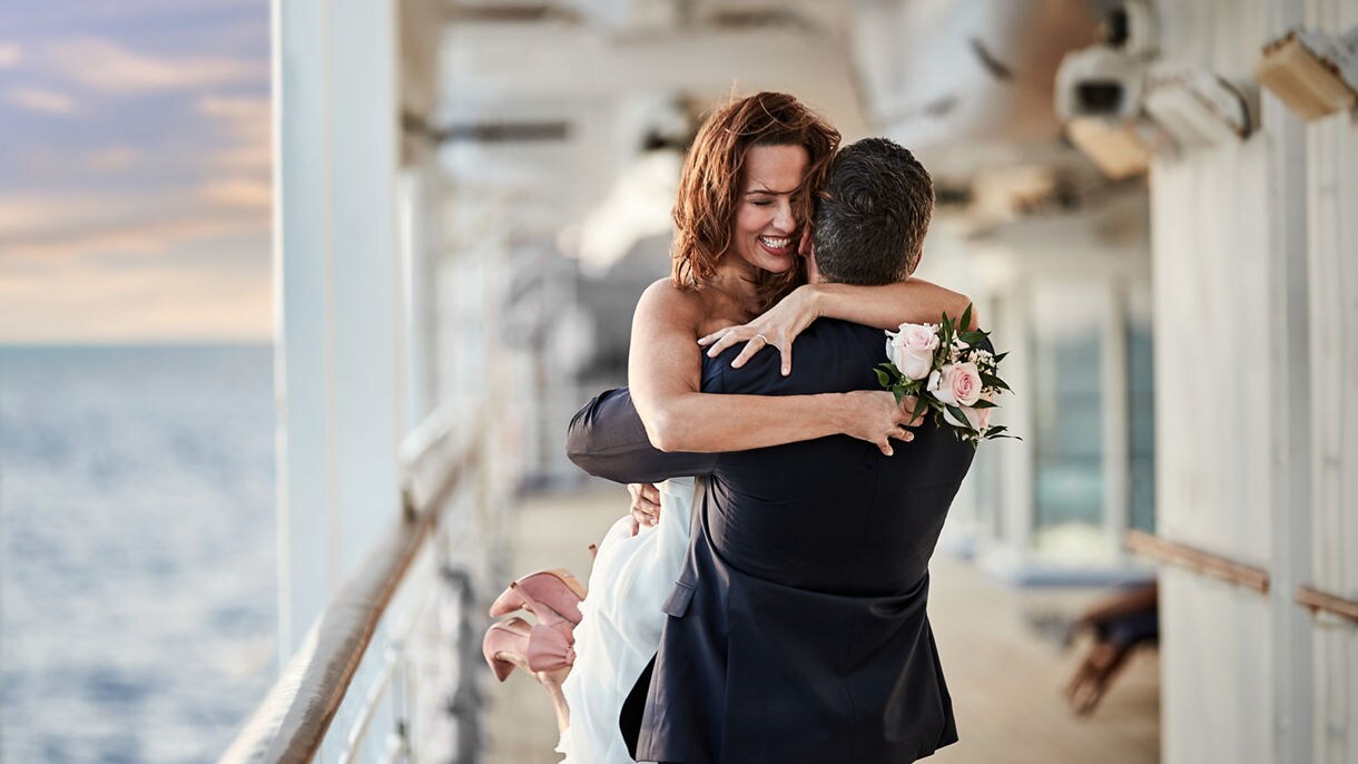 https://assets.princess.com/is/image/princesscruises/wedding-dress-tuxedo-on-deck-bride-groom-joy:16x9?ts=1698256093990