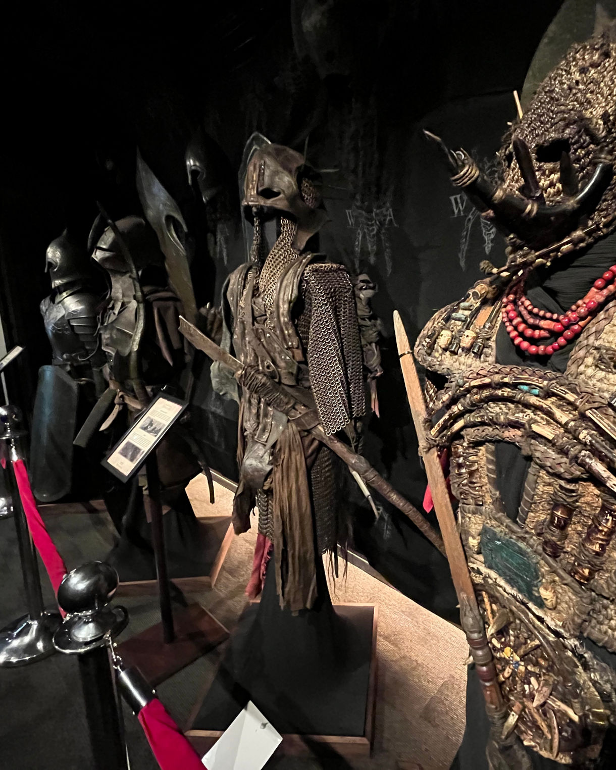 Display of intricately detailed fantasy armor and props at Wētā Workshop in Wellington, including chainmail, sculpted helmets and beaded adornments.